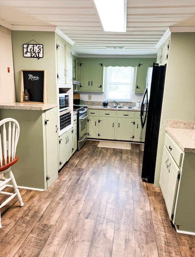 kitchen featuring green cabinets, ornamental molding, and appliances with stainless steel finishes