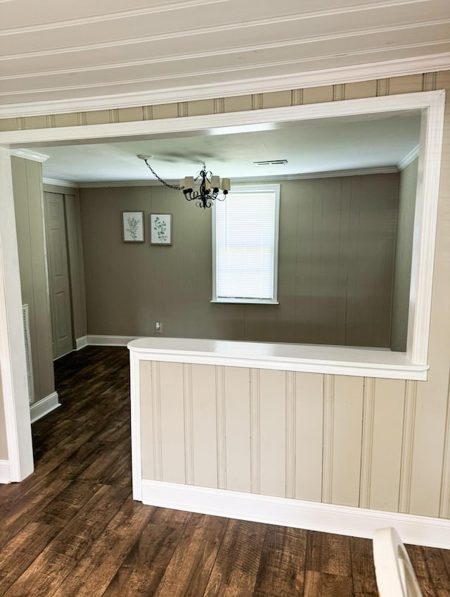 unfurnished room featuring dark wood-type flooring, ornamental molding, and a chandelier