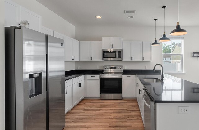 7780 Montview Rd, North Charleston, SC 29418 - kitchen with stainless steel appliances, a sink, dark countertops, light wood-type flooring, and a peninsula