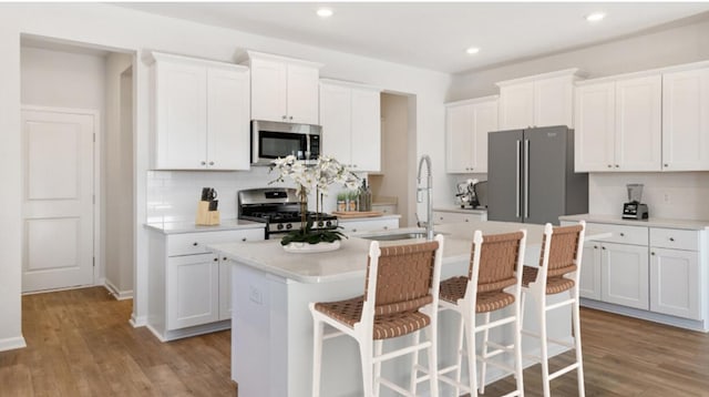 kitchen with white cabinetry, light wood-style floors, a kitchen island with sink, and stainless steel appliances