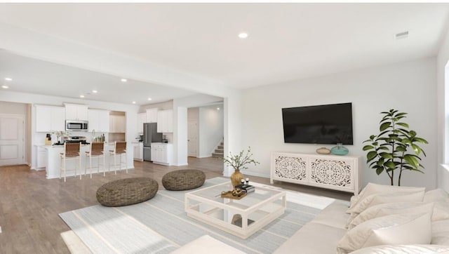 living room featuring stairway, recessed lighting, light wood-type flooring, and baseboards