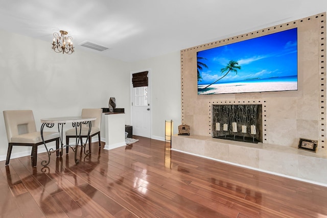 living room featuring baseboards, wood finished floors, visible vents, and a notable chandelier