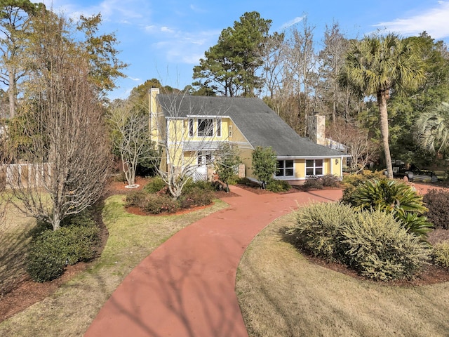 view of front of house featuring a chimney, a front yard, and stucco siding