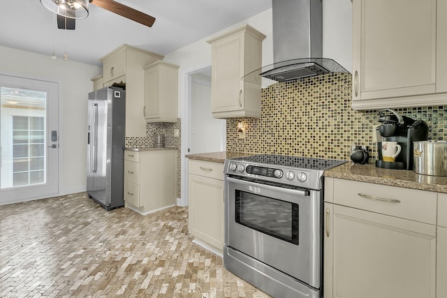 kitchen with decorative backsplash, cream cabinets, appliances with stainless steel finishes, ceiling fan, and exhaust hood