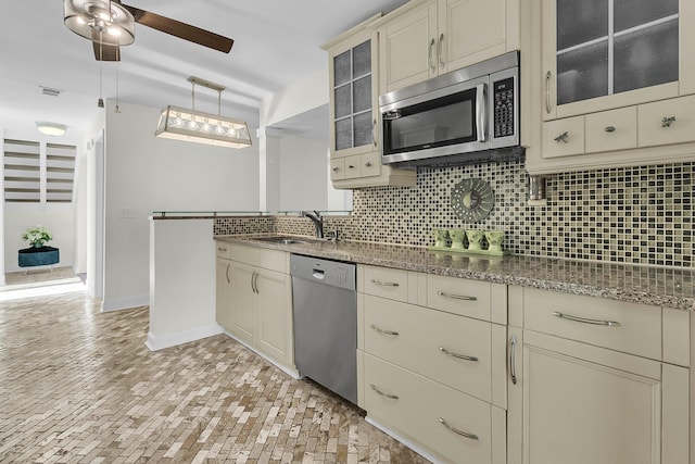 kitchen with stainless steel appliances, glass insert cabinets, backsplash, and cream cabinets