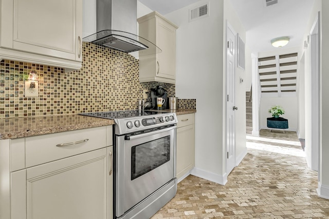 kitchen featuring light stone counters, range hood, stainless steel electric stove, tasteful backsplash, and visible vents