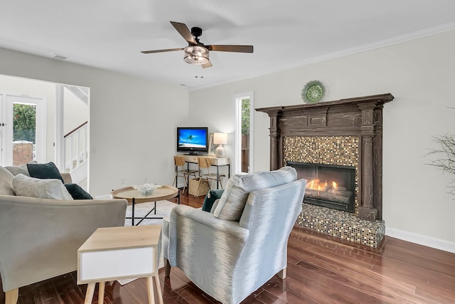 living area featuring baseboards, dark wood-style flooring, a wealth of natural light, and a tile fireplace