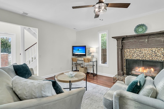 living area featuring baseboards, visible vents, a tile fireplace, stairway, and wood finished floors