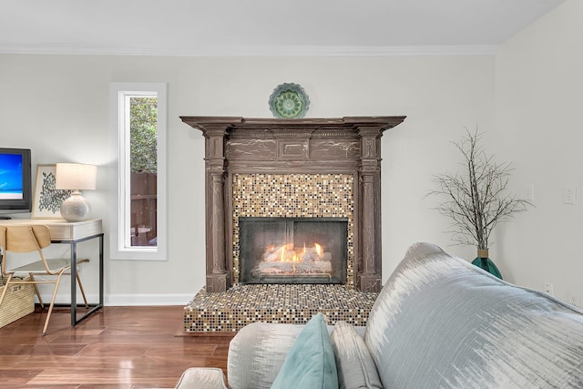 interior details with crown molding, a fireplace, baseboards, and wood finished floors