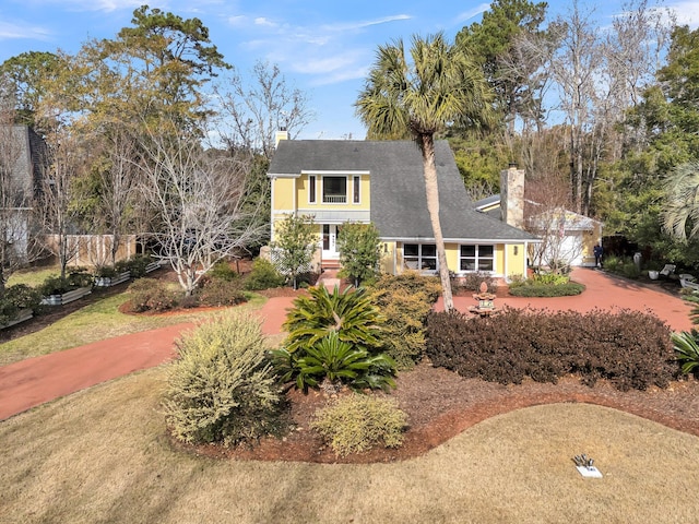 view of front of property featuring driveway, a garage, and a chimney