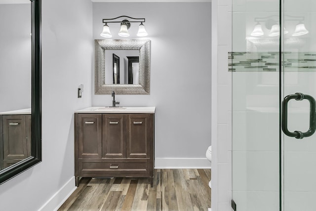 bathroom with an enclosed shower, baseboards, wood finished floors, and vanity