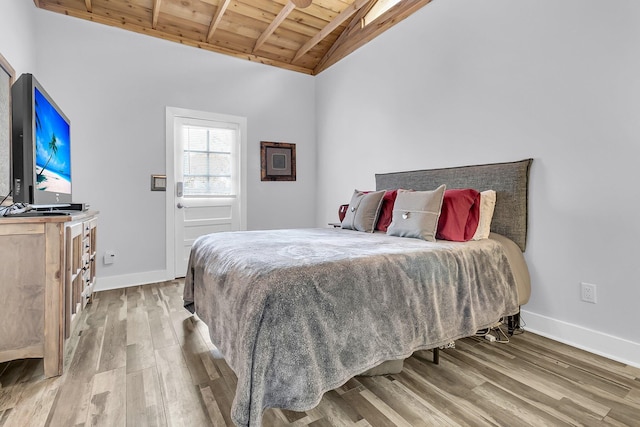 bedroom featuring vaulted ceiling with beams, wood ceiling, baseboards, and wood finished floors