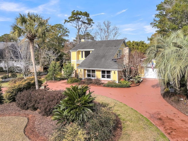 view of front of property with driveway, a chimney, and stucco siding