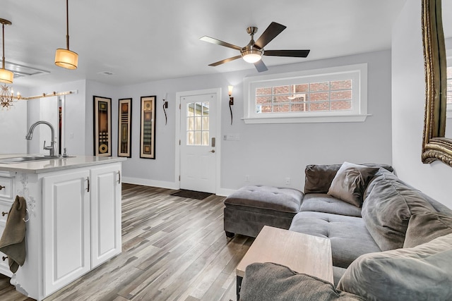 living area with a ceiling fan, light wood-type flooring, and baseboards