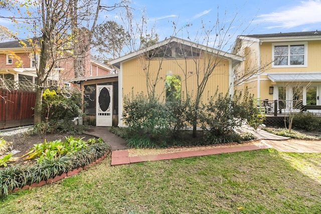 view of front of home with a front yard, fence, and a sunroom