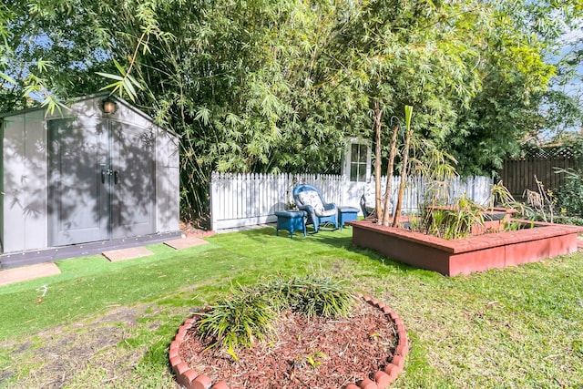 view of yard with an outbuilding, a storage unit, a fenced backyard, and a vegetable garden