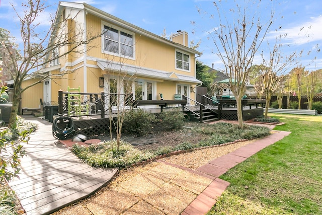 back of property with a yard, a chimney, french doors, and a wooden deck