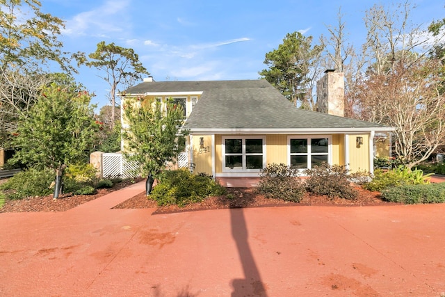 view of front of property with a chimney, fence, and roof with shingles