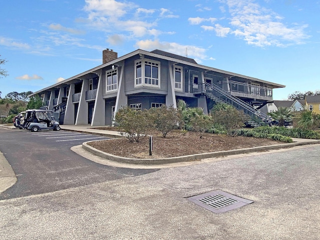 view of property with uncovered parking and stairs