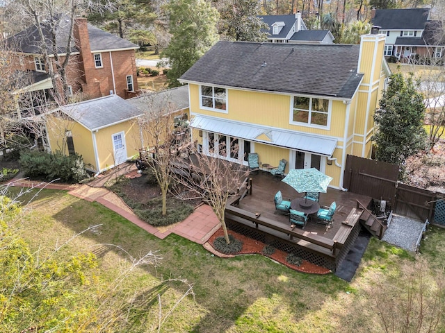 rear view of house with a wooden deck, a lawn, a chimney, fence, and an outdoor structure