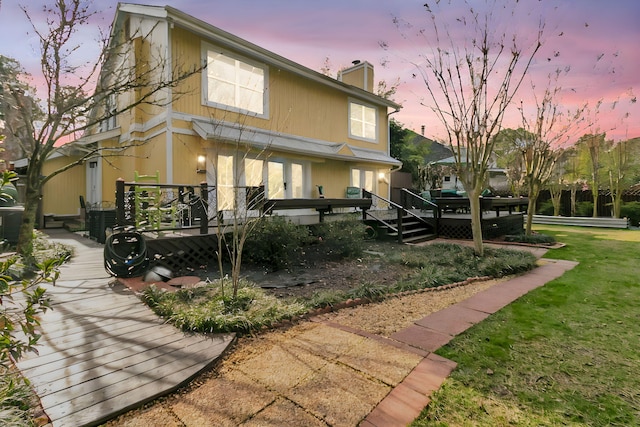 back of property featuring a wooden deck, a chimney, and a yard