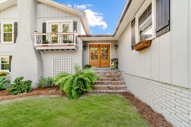 property entrance featuring a balcony, a yard, and french doors