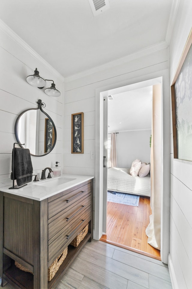 bathroom with vanity, wood-type flooring, and crown molding