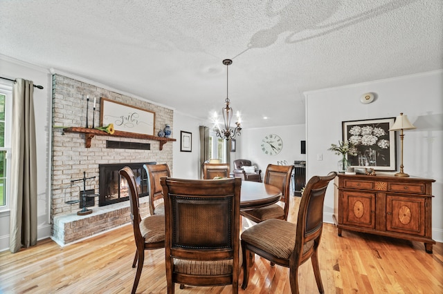 dining space featuring a fireplace, a chandelier, a textured ceiling, and light wood-type flooring