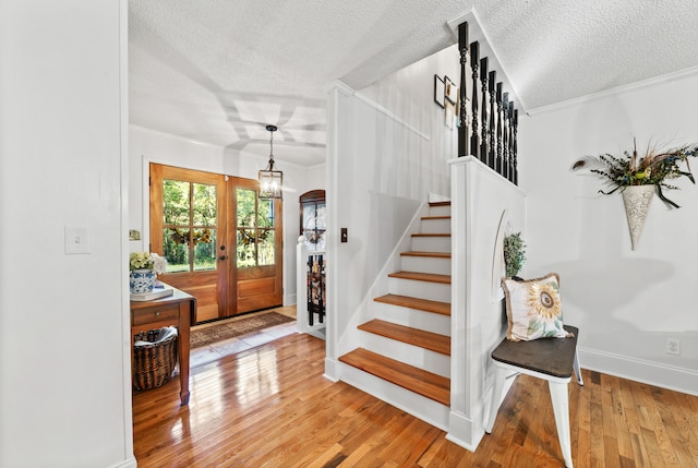 entrance foyer with ornamental molding, french doors, hardwood / wood-style floors, and a textured ceiling