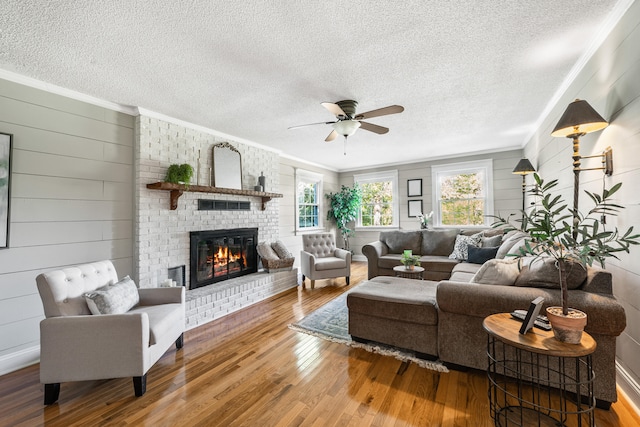 living room featuring ornamental molding, a fireplace, wood-type flooring, and a textured ceiling