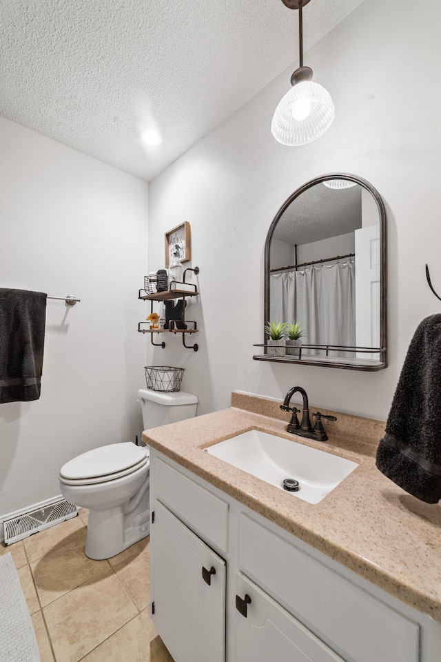 bathroom featuring tile patterned flooring, vanity, toilet, and a textured ceiling