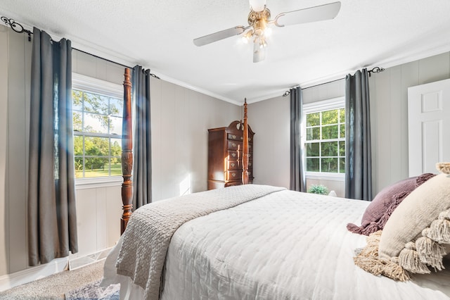 carpeted bedroom featuring ornamental molding, multiple windows, a textured ceiling, and ceiling fan