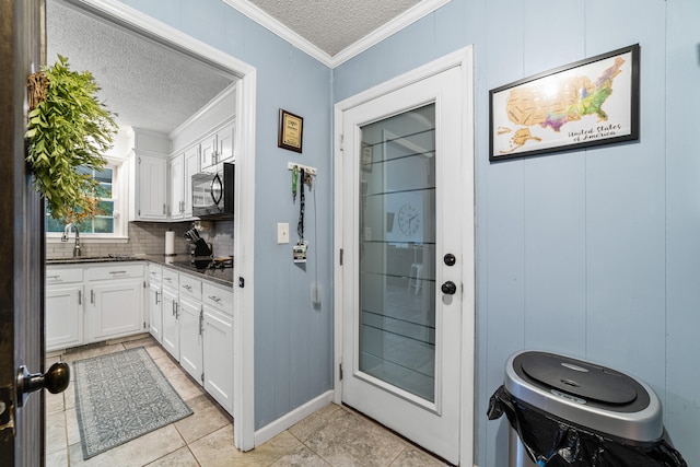 entryway featuring wood walls, a textured ceiling, light tile patterned floors, and crown molding