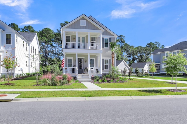 view of front of property featuring board and batten siding, a porch, a balcony, and a front lawn