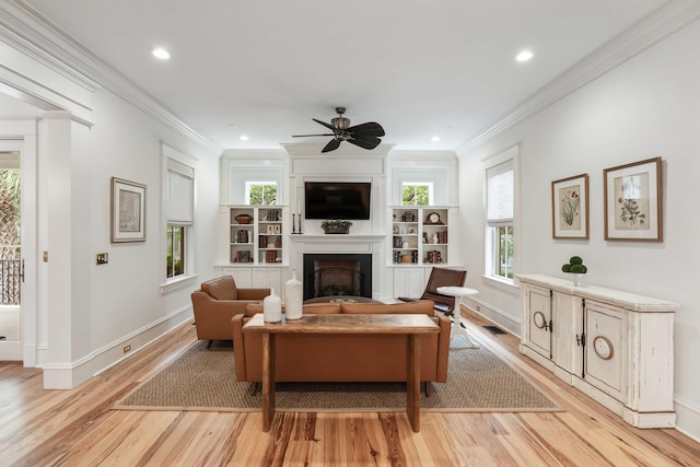 living area featuring a large fireplace, light wood-style flooring, ornamental molding, baseboards, and recessed lighting
