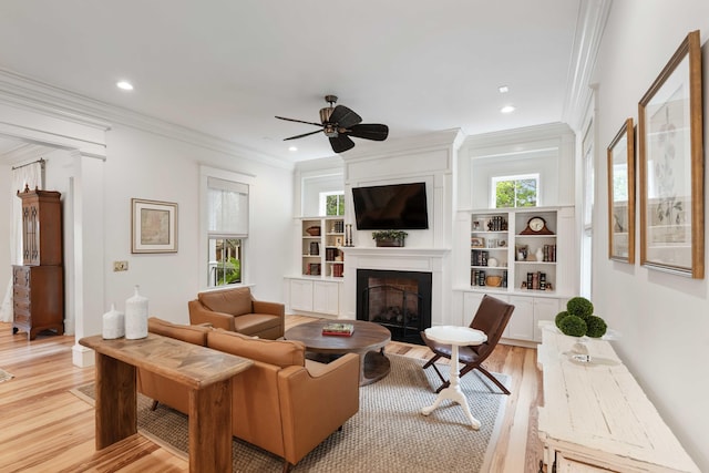 living room with light wood-style flooring, a large fireplace, ceiling fan, crown molding, and recessed lighting