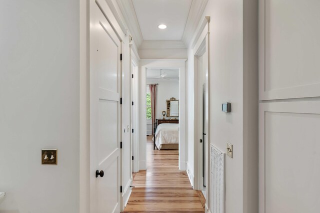 hallway with crown molding, light wood-type flooring, baseboards, and recessed lighting