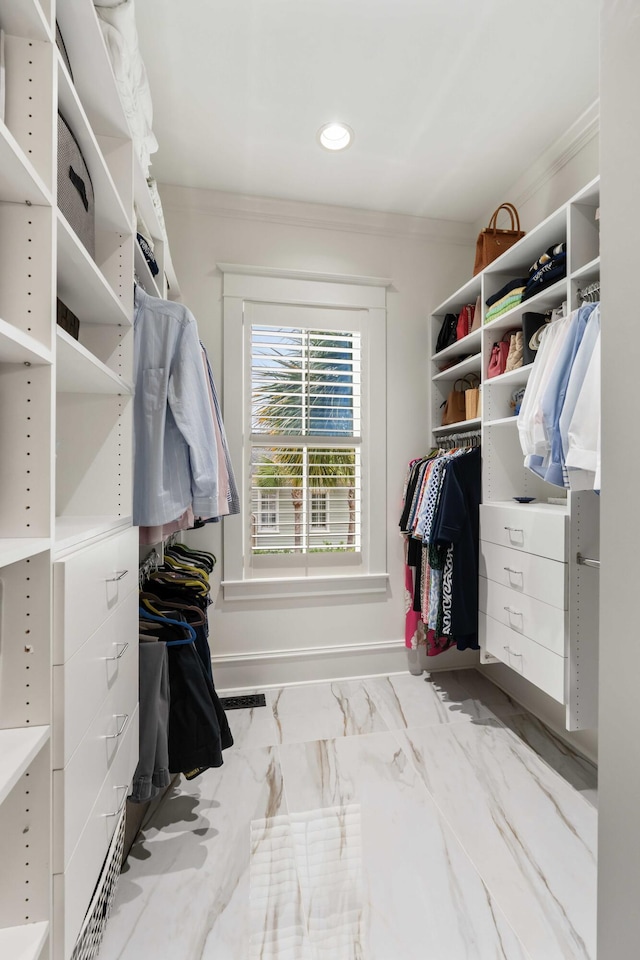 walk in closet featuring marble finish flooring