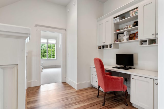 office area featuring built in desk, light wood-type flooring, and baseboards
