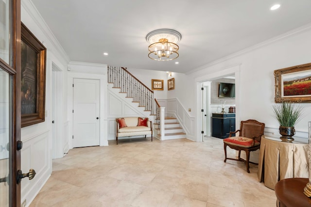 entrance foyer featuring stairway, crown molding, a decorative wall, a chandelier, and recessed lighting