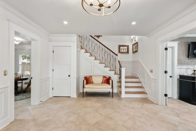 staircase with a decorative wall, a chandelier, a wainscoted wall, and ornamental molding