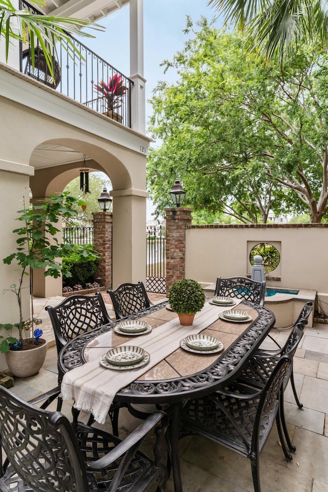 view of patio featuring outdoor dining space, a balcony, and fence