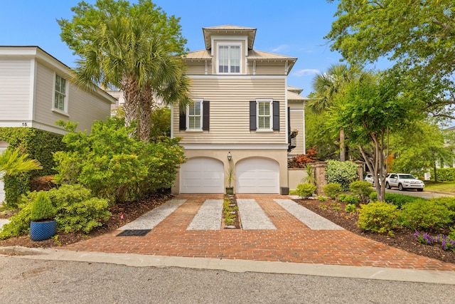 view of front of property with decorative driveway, stucco siding, a garage, metal roof, and a standing seam roof