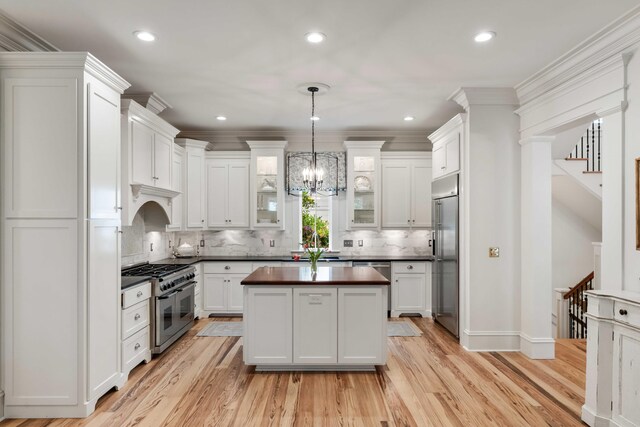 kitchen featuring premium appliances, white cabinets, a center island, recessed lighting, and ornamental molding