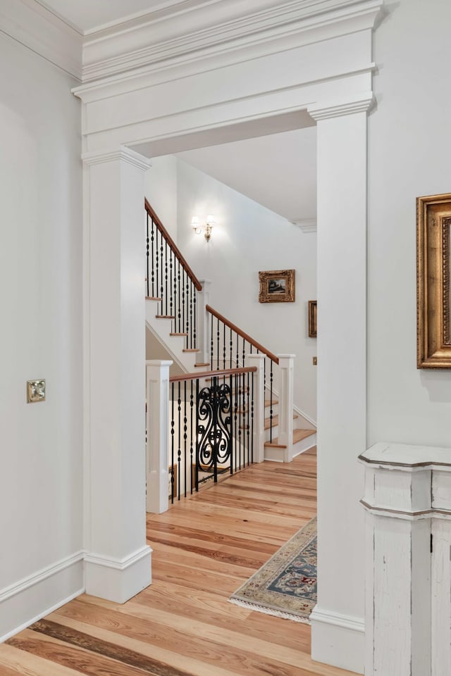 stairs featuring wood finished floors, ornamental molding, and baseboards