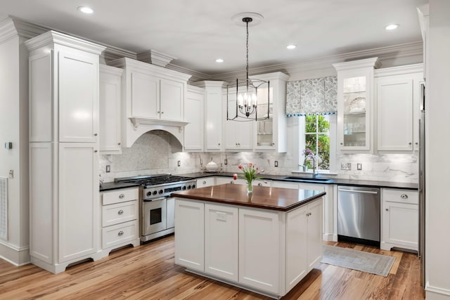 kitchen featuring stainless steel appliances, butcher block countertops, white cabinetry, and recessed lighting