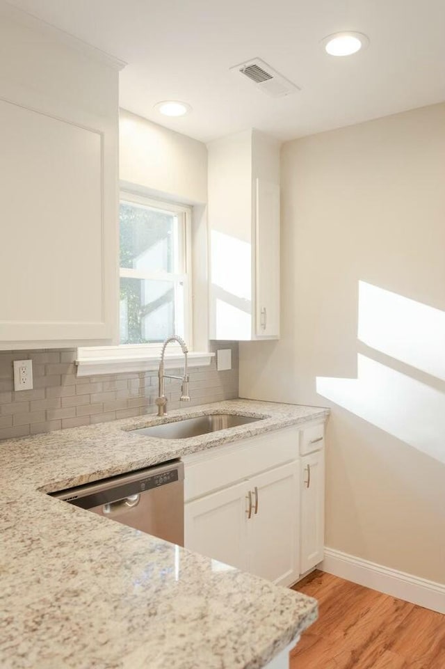 kitchen featuring visible vents, white cabinetry, a sink, dishwasher, and backsplash