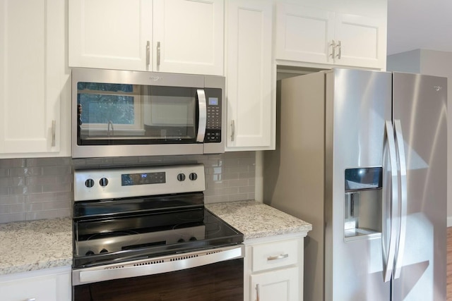 kitchen featuring backsplash, appliances with stainless steel finishes, white cabinetry, and light stone countertops