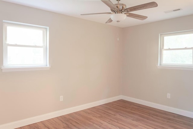 empty room with visible vents, light wood-style flooring, a ceiling fan, and baseboards