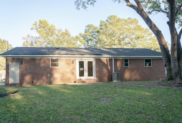 rear view of house with french doors, brick siding, cooling unit, and a lawn